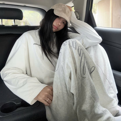Person sitting in a car wearing a white hoodie and holding a white blanket.